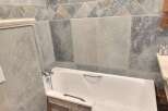 Relax in this charming bathroom featuring a bathtub and stylish tilework.