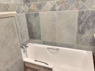 Relax in this charming bathroom featuring a bathtub and stylish tilework.