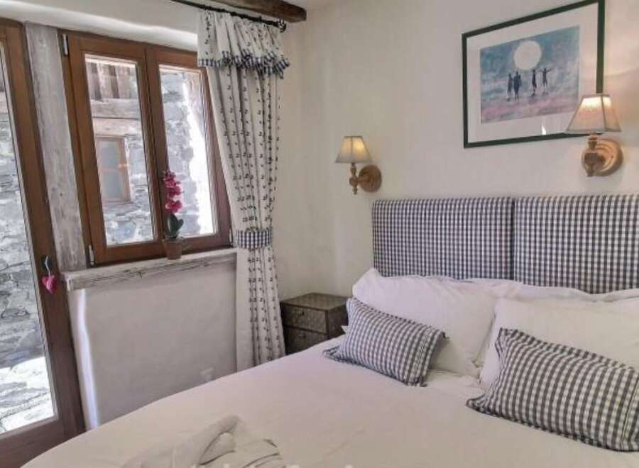 Charming bedroom with stone wall view and gingham details.