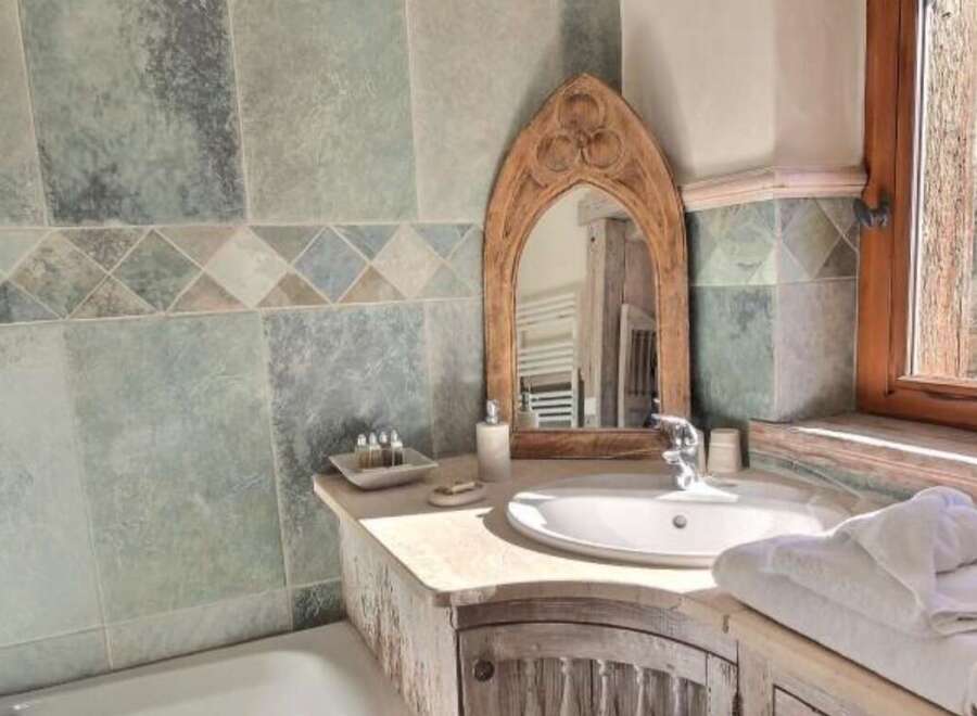 This stunning bathroom boasts a rustic-chic design with slate tile walls and a unique wooden vanity.