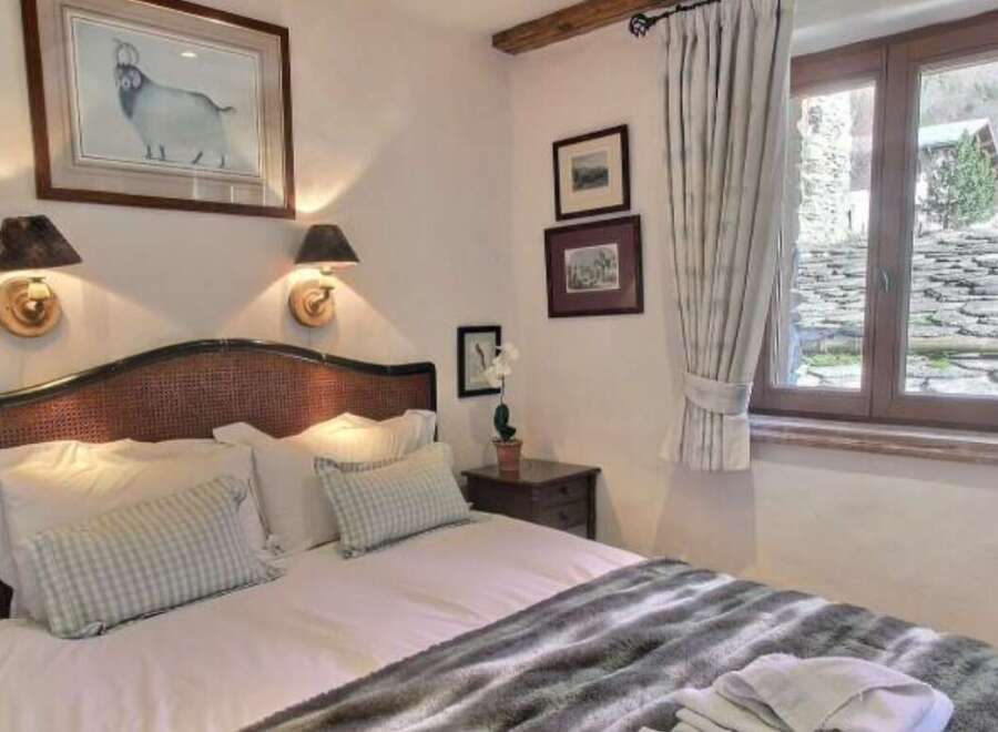 Cozy bedroom with a comfortable bed, featuring a rustic wooden headboard and soft, plush bedding.