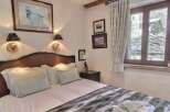 Cozy bedroom with a comfortable bed, featuring a rustic wooden headboard and soft, plush bedding.