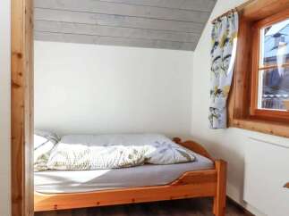 Cozy bedroom featuring a wooden bed frame and a charming window with floral curtains.