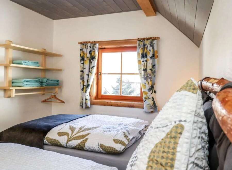 This cozy bedroom features a charming window with floral curtains, creating a warm and inviting atmosphere.