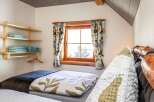This cozy bedroom features a charming window with floral curtains, creating a warm and inviting atmosphere.