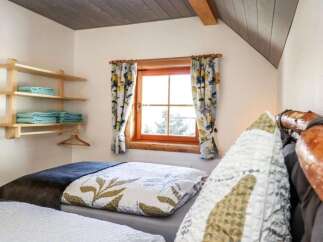 This cozy bedroom features a charming window with floral curtains, creating a warm and inviting atmosphere.
