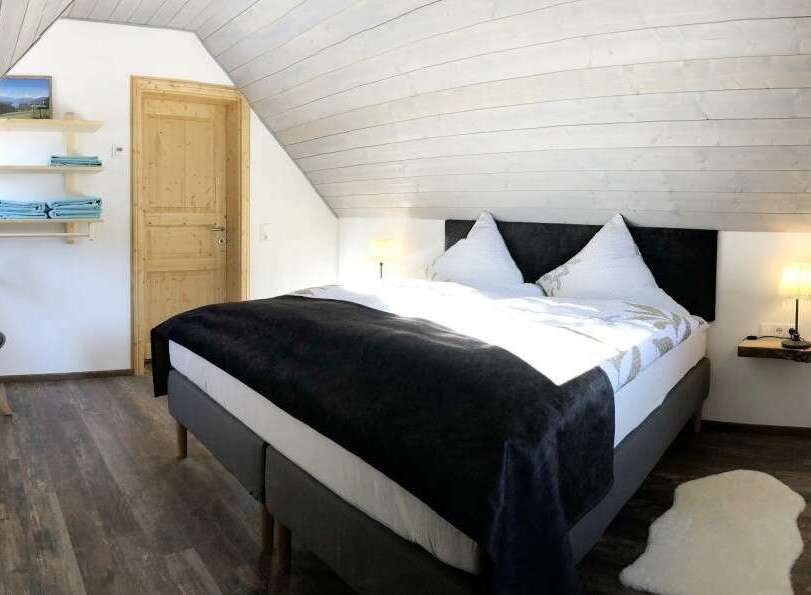 This cozy bedroom features a comfortable bed with a dark blanket, perfect for a relaxing stay.