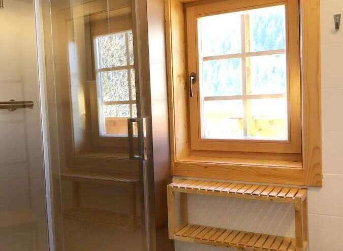 This bathroom features a modern glass shower enclosure, complemented by a wooden window frame that adds warmth and character.