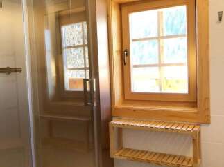 This bathroom features a modern glass shower enclosure, complemented by a wooden window frame that adds warmth and character.