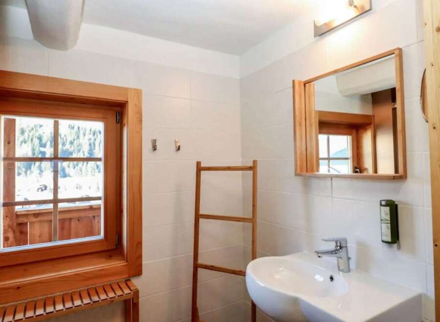 This charming bathroom features a rustic wooden window and mirror frame, adding warmth and character to the space.