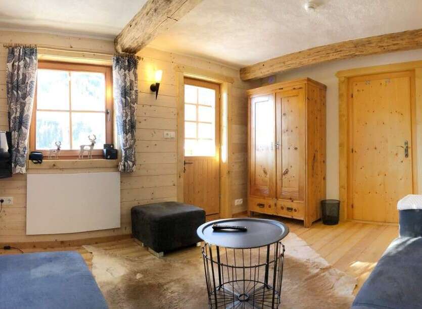 Discover the charm of this cozy cabin-style living room, featuring warm wooden walls and exposed beams.