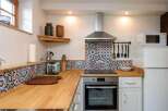 This charming kitchen features a unique mosaic backsplash and warm wooden countertops, creating a cozy and inviting atmosphere.