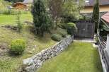Discover a charming property with a beautifully landscaped garden, featuring a stone retaining wall and lush greenery.