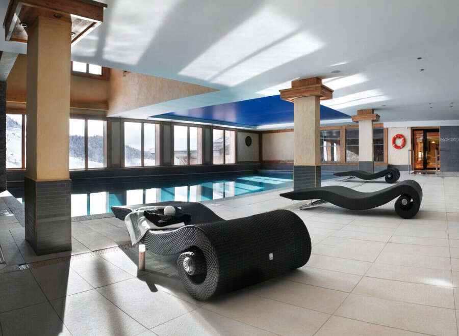 Indulge in luxury at our resort's stunning indoor pool area, complete with sleek, modern chaise lounges perfect for relaxation after a day on the slopes.