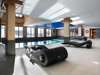Indulge in luxury at our resort's stunning indoor pool area, complete with sleek, modern chaise lounges perfect for relaxation after a day on the slopes.