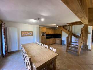 This stunning chalet boasts a spacious open-plan living area with a large wooden dining table perfect for family gatherings.