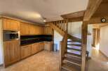 This charming chalet boasts a rustic kitchen with light wood cabinets and a tiled floor, creating a warm and inviting atmosphere.