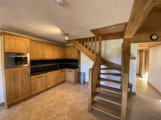 This charming chalet boasts a rustic kitchen with light wood cabinets and a tiled floor, creating a warm and inviting atmosphere.