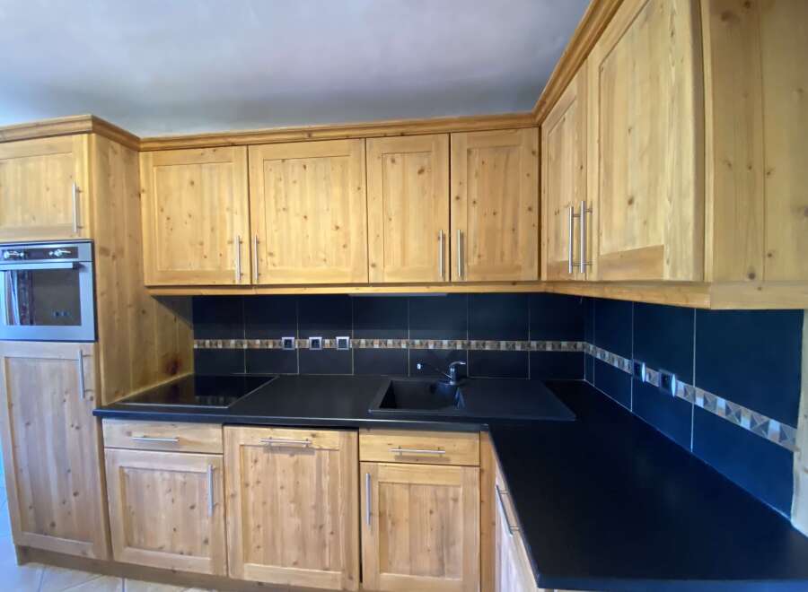 This charming kitchen boasts light wood cabinets and a sleek, dark countertop, creating a warm and inviting atmosphere.
