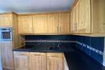 This charming kitchen boasts light wood cabinets and a sleek, dark countertop, creating a warm and inviting atmosphere.