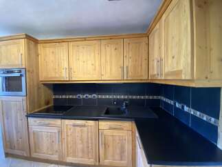This charming kitchen boasts light wood cabinets and a sleek, dark countertop, creating a warm and inviting atmosphere.