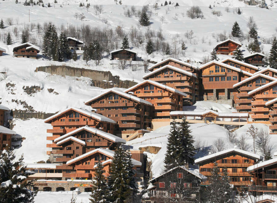 Discover the charm of these stunning wooden chalets nestled in a snowy mountain landscape.