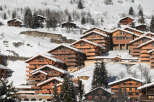 Discover the charm of these stunning wooden chalets nestled in a snowy mountain landscape.