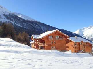 Discover the charm of this stunning wooden chalet nestled in a picturesque snowy landscape.