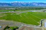 This expansive property boasts lush green fields, ideal for agriculture, with a tranquil waterway meandering through the landscape.
