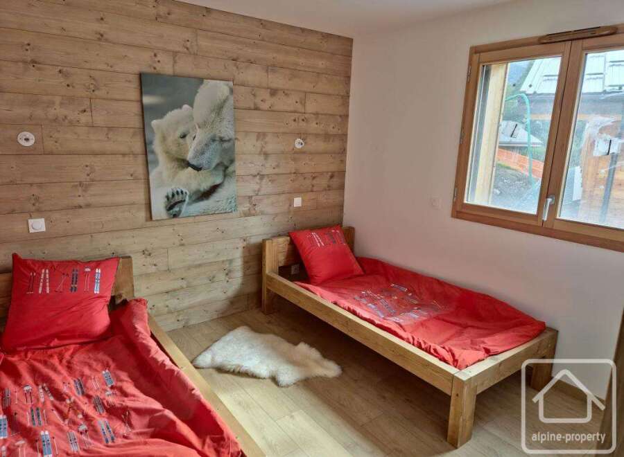 This cozy bedroom features two single beds with vibrant red bedding, perfect for a comfortable stay.