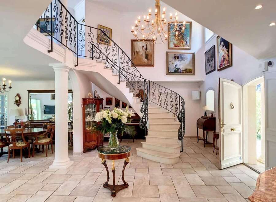 This stunning property boasts a grand entrance with a sweeping staircase and elegant chandeliers.