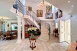 This stunning property boasts a grand entrance with a sweeping staircase and elegant chandeliers.