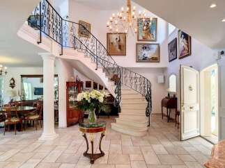 This stunning property boasts a grand entrance with a sweeping staircase and elegant chandeliers.