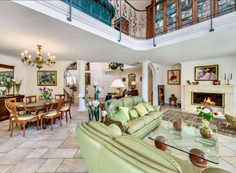 This stunning property boasts a grand, open-plan living area with high ceilings and a beautiful fireplace, creating a warm and inviting atmosphere.