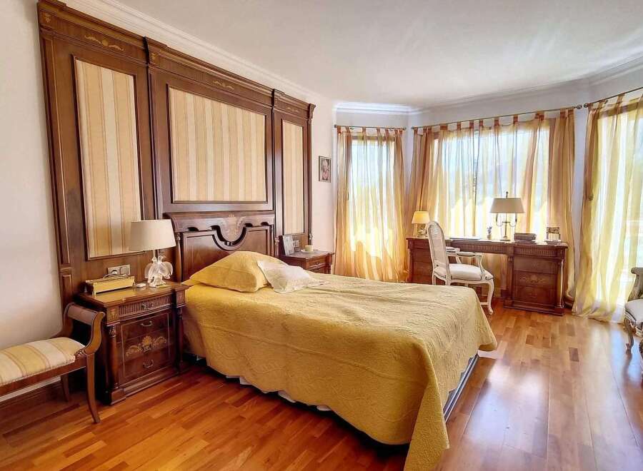 Luxurious bedroom with hardwood floors, custom wood paneling, and elegant yellow bedding.