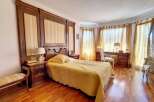 Luxurious bedroom with hardwood floors, custom wood paneling, and elegant yellow bedding.