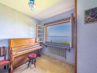 This stunning property boasts breathtaking lake views from a charming room featuring a vintage piano.