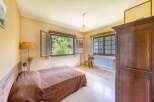 Charming bedroom with large windows offering abundant natural light and views of lush greenery.