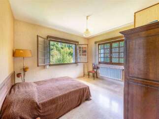 Charming bedroom with large windows offering abundant natural light and views of lush greenery.