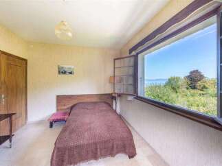 This charming bedroom boasts a tranquil atmosphere with its rustic wooden bed and stunning lake views.