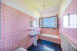This charming bathroom boasts vintage pink tiles, creating a unique and nostalgic atmosphere.