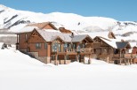 Luxury mountain home undergoing roof construction in a stunning snowy landscape.