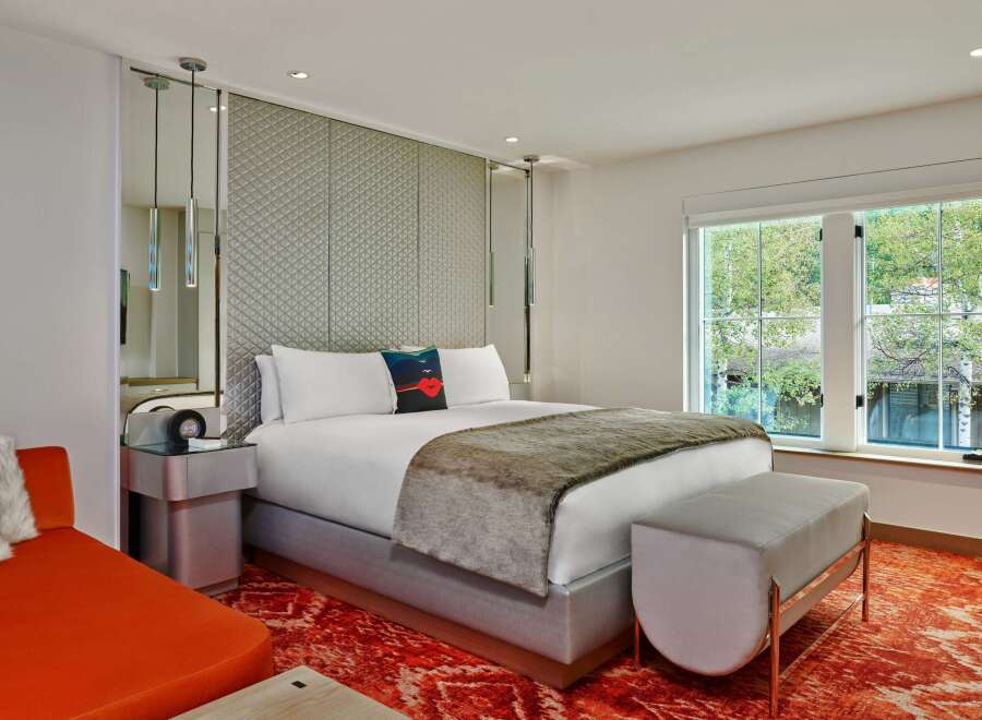 Stylish hotel room featuring a comfortable king-size bed with a plush throw, a unique headboard, and a modern side table.