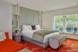 Stylish hotel room featuring a comfortable king-size bed with a plush throw, a unique headboard, and a modern side table.