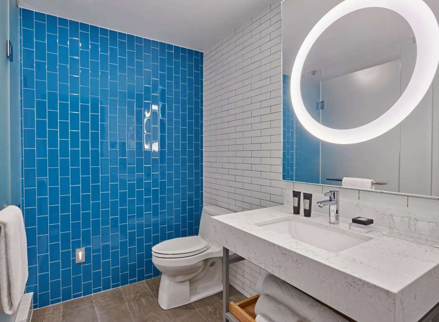 This modern bathroom boasts a stylish blue tile shower, complemented by crisp white subway tiles on the walls.