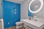 This modern bathroom boasts a stylish blue tile shower, complemented by crisp white subway tiles on the walls.