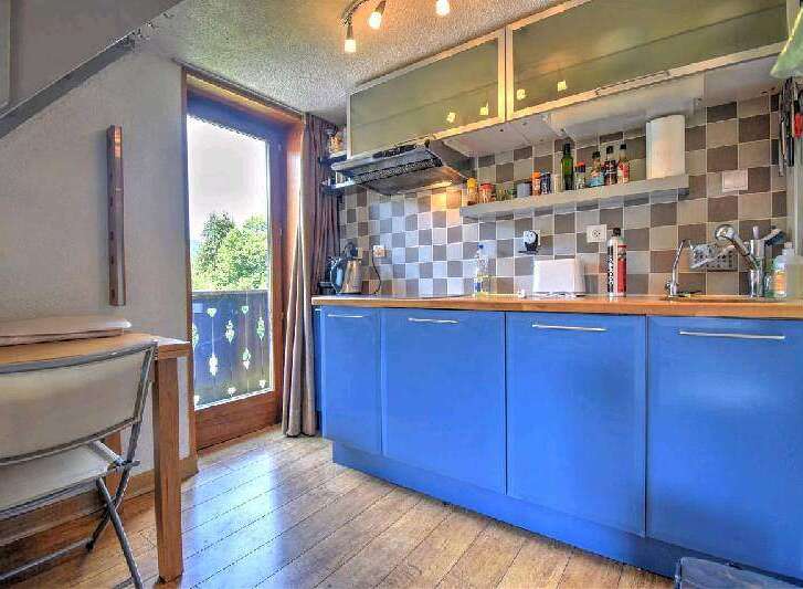Charming apartment featuring a bright kitchen with blue cabinets and wooden countertops.
