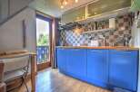 Charming apartment featuring a bright kitchen with blue cabinets and wooden countertops.