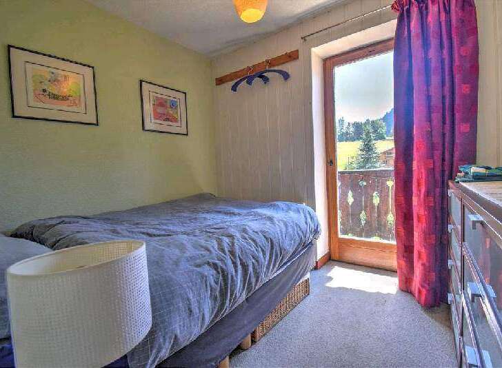 Cozy bedroom with a double bed and stunning mountain views from the balcony.
