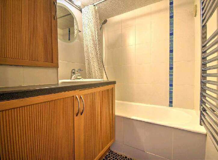 This charming bathroom boasts a sleek, modern design with wood-paneled cabinetry and a bathtub.